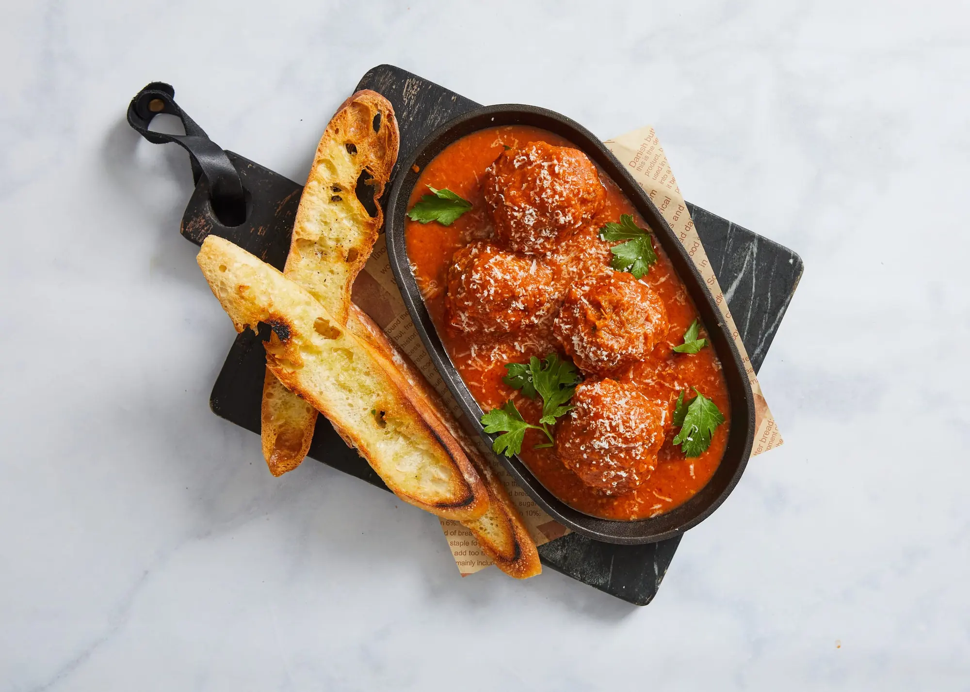 Donatella’s meatballs in tomato sauce, in a cast-iron dish with grilled bread